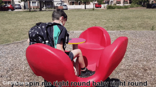 Boy Sitting On Red Flower Merry Go Round GIF