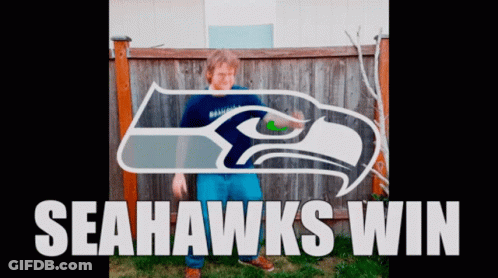 Boy Standing In Front Of Seahawks Logo GIF