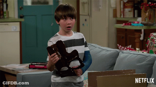 Boy With Arm Cast Holding Toy In Front Of Netflix Box GIF