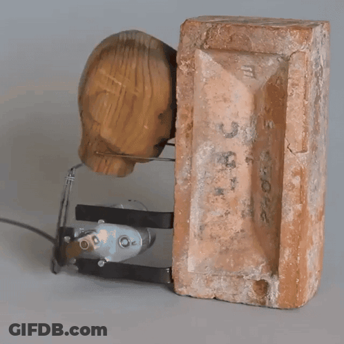 Boy With Backpack Squatting Against Brick Wall GIF