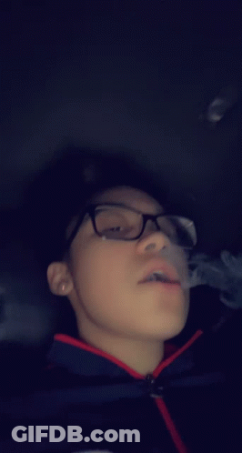 Boy With Glasses Smoking Cigarette In Dark Room GIF