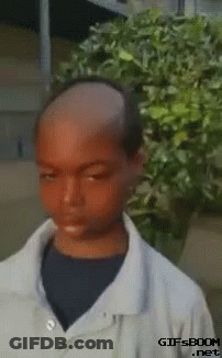 Boy With Shaved Head In Front Of Bush GIF