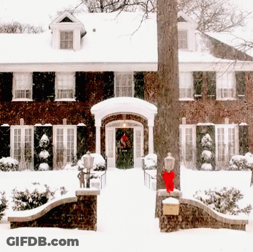 Brick House Covered In Snow With Red Bow On Door GIF