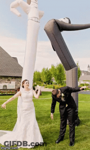 Bride And Groom Posing With Large Inflatable Man GIF