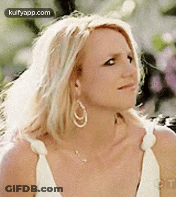 Britney Spears Is Wearing A White Dress And Earrings And Looking At The Camera . GIF