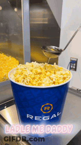Bucket Of Regal Popcorn Being Poured With Spoon GIF