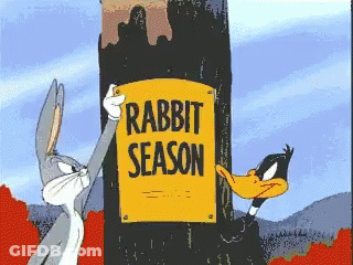 Bugs Bunny And Daffy Duck Are Holding A Sign That Says Rabbit Season GIF