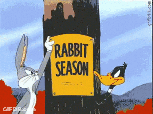 Bugs Bunny And Daffy Duck Hold Up A Sign That Says Rabbit Season GIF