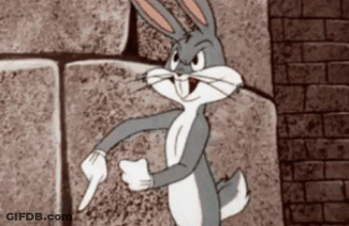 Bugs Bunny Is Standing In Front Of A Brick Wall Pointing GIF