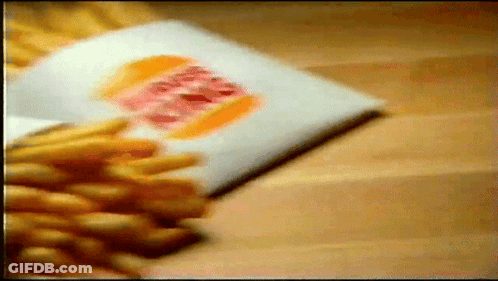 Bunch Of French Fries On Wooden Table GIF