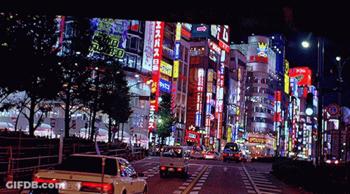 Busy City Street At Night With Sign Saying A GIF