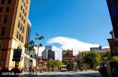 Busy City Street With Downtown Sign GIF