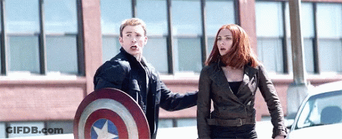 Captain America And Black Widow Are Standing Next To Each Other On The Street . GIF