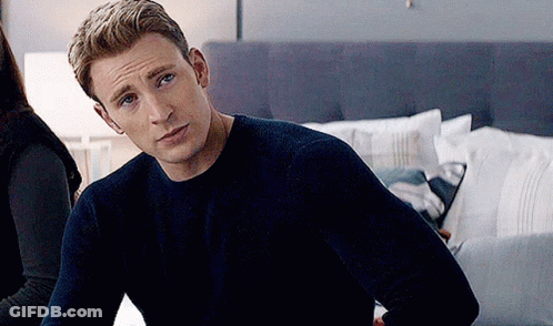 Captain America Is Wearing A Blue Sweater And Sitting On A Bed . GIF