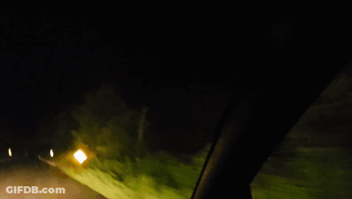 Car Driving Down Road At Night With Yellow Sign GIF