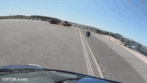 Car Driving Down Road With Tire On Side GIF