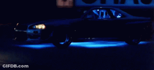Car Driving Down Street At Night With Blue Lights GIF
