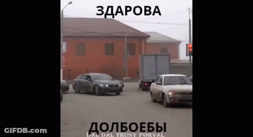 Car Driving Down Street In Front Of Building Saying Здорова GIF