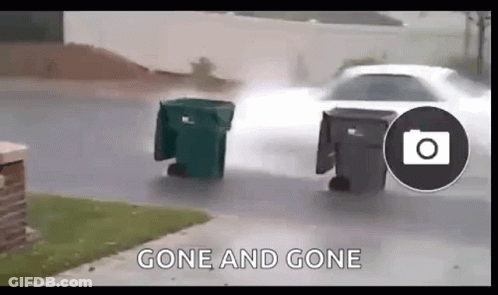 Car Driving Down Street Next To Trash Can In Rain GIF