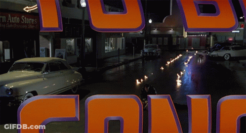 Car Driving Down Street Past Ruth Store GIF