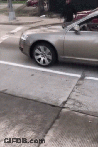 Car Driving Down Street With Person In Background GIF
