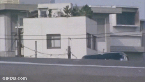 Car Parked By White Building With Rooftop Garden GIF