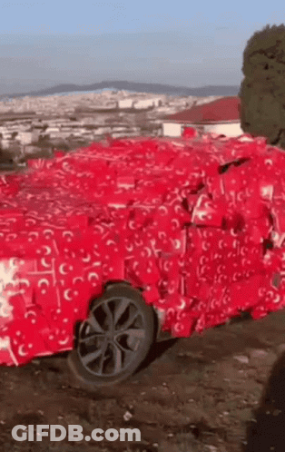 Car Wrapped In Red Tissue Paper In Dirt GIF