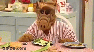 Cartoon Character Sitting At Table With Plate Of Food GIF