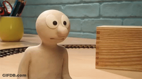 Cartoon Character Sitting On Table Next To Wooden Box GIF