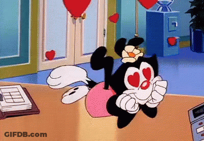 Cartoon Character With Hearts In Eyes Sitting On Desk GIF