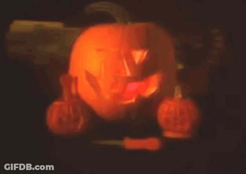 Carved Pumpkin Lit Up In Dark Surrounded By Pumpkins GIF