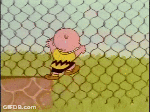 Charlie Brown Is Standing Behind A Chain Link Fence In A Cartoon . GIF
