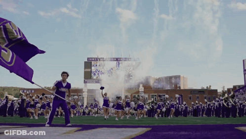 Cheerleader Holding Purple Flag In Front Of James Madison University Scoreboard GIF
