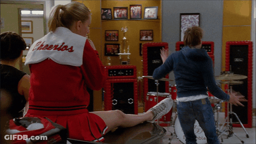 Cheerleader In Cheerios Jacket On Bench GIF