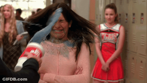 Cheerleader In Gray Uniform Behind Woman With Cup On Head GIF