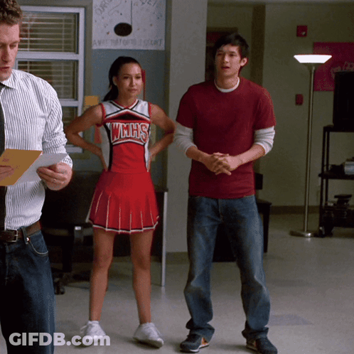 Cheerleader In WMHS Uniform Next To Man In Red Shirt GIF
