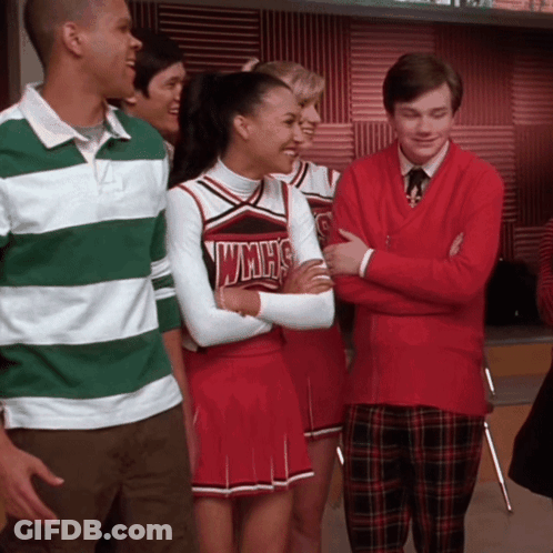 Cheerleader In WMHS Uniform Next To Man In Red Sweater GIF