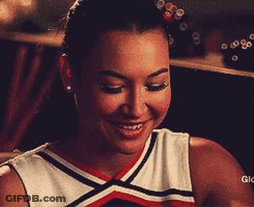 Cheerleader Smiling Holding Stick In Mouth GIF