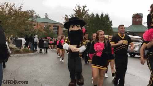 Cheerleaders Marching With Mascot In Black Hat GIF