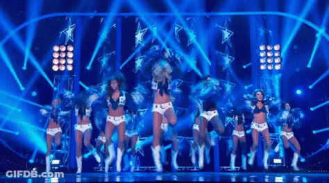 Cheerleaders Performing On Stage With Blue Lights And Stars GIF