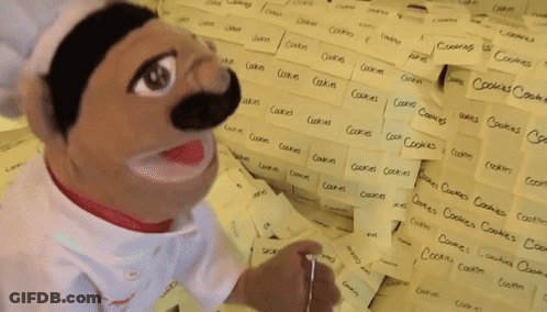 Chef Puppet In Front Of Sticky Note Wall With Cookies GIF