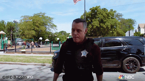 Chicago Police Officer Walking Down Street In Front Of Park GIF