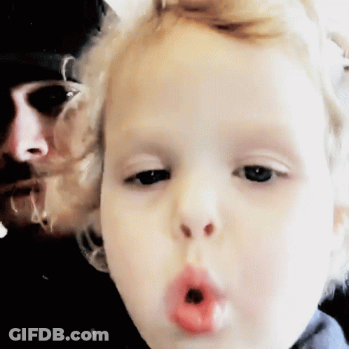 Child Blowing Kiss With Man In Background GIF