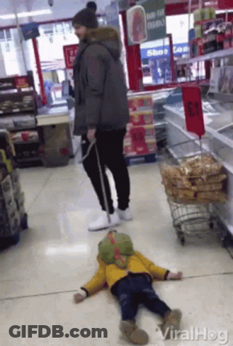 Child Laying On Store Floor With Man Standing Behind GIF