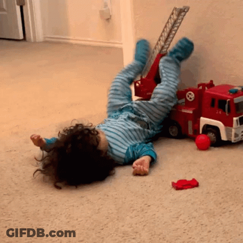 Child Lying Next To Toy Fire Truck GIF