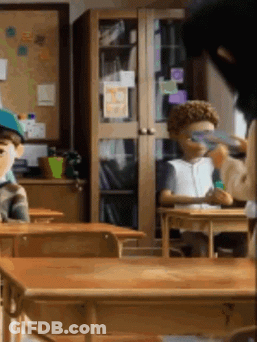 Children Sitting At Desks In Classroom With Bulletin Board GIF