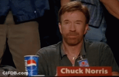 Chuck Norris Is Sitting At A Table With A Sign That Says Chuck Norris On It . GIF