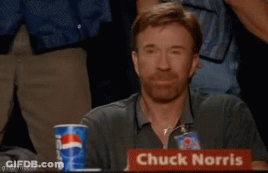 Chuck Norris Is Sitting At A Table With His Fist Up GIF