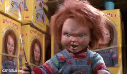 Chucky Doll Holding Scissors Beside Stack Of Chucky Dolls GIF