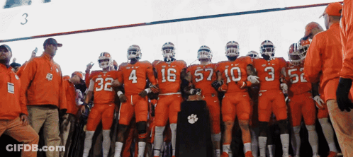 Clemson Football Players In Orange Uniforms With Trophy GIF